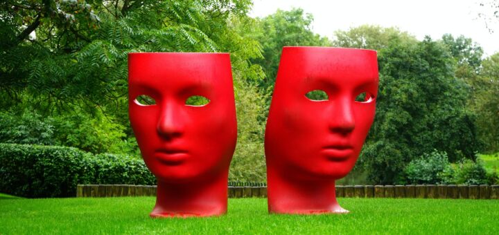 red human face monument on green grass field