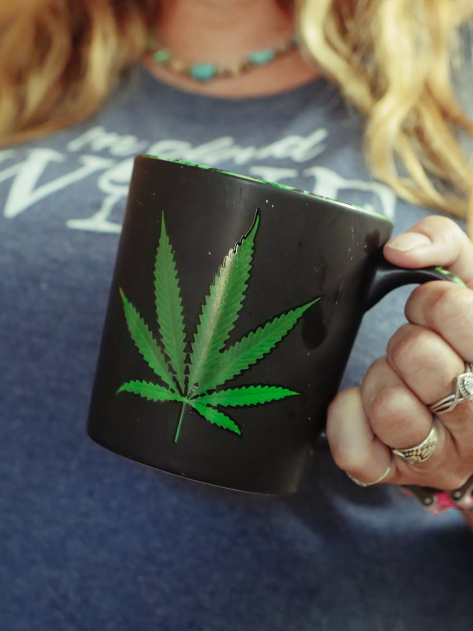 person holding black and green leaf print ceramic mug