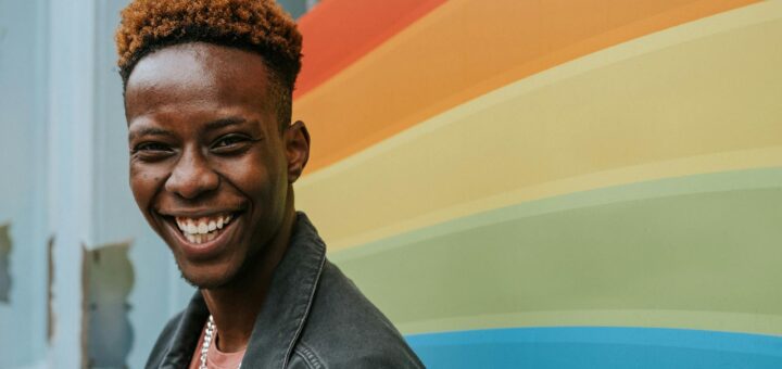 positive young black guy laughing near graffiti wall with rainbow flag